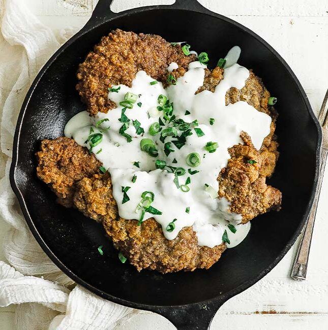 cast iron skillet with chicken fried steak and gravy