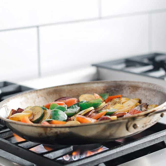sautéing vegetables in a pan over a flame