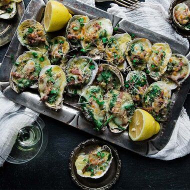 oysters rockefeller served on a platter with lemons