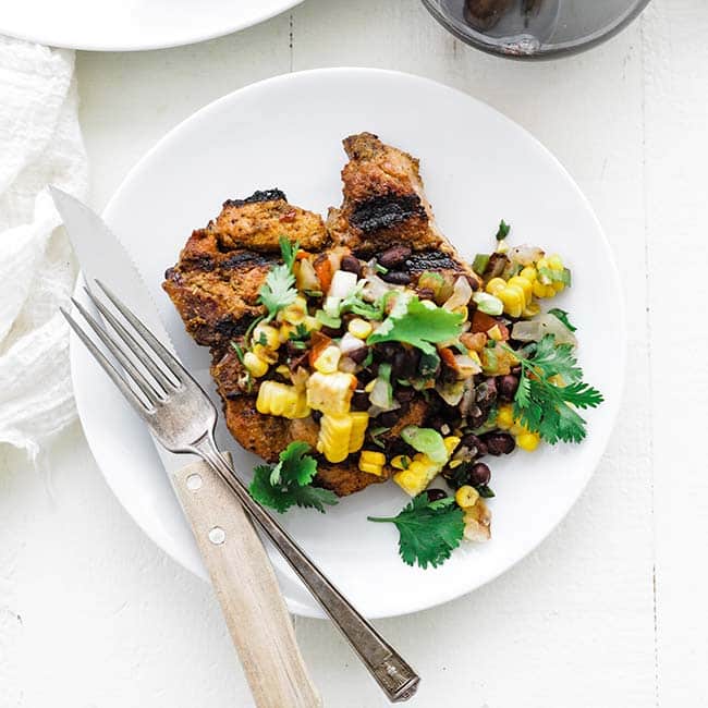 pork chops on a plate with a corn salsa