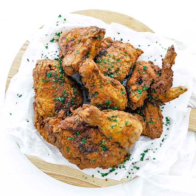 fried chicken garnished with chop parsley on parchment paper