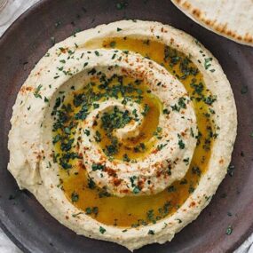 plate of swirled homemade hummus with olive oil and parsley