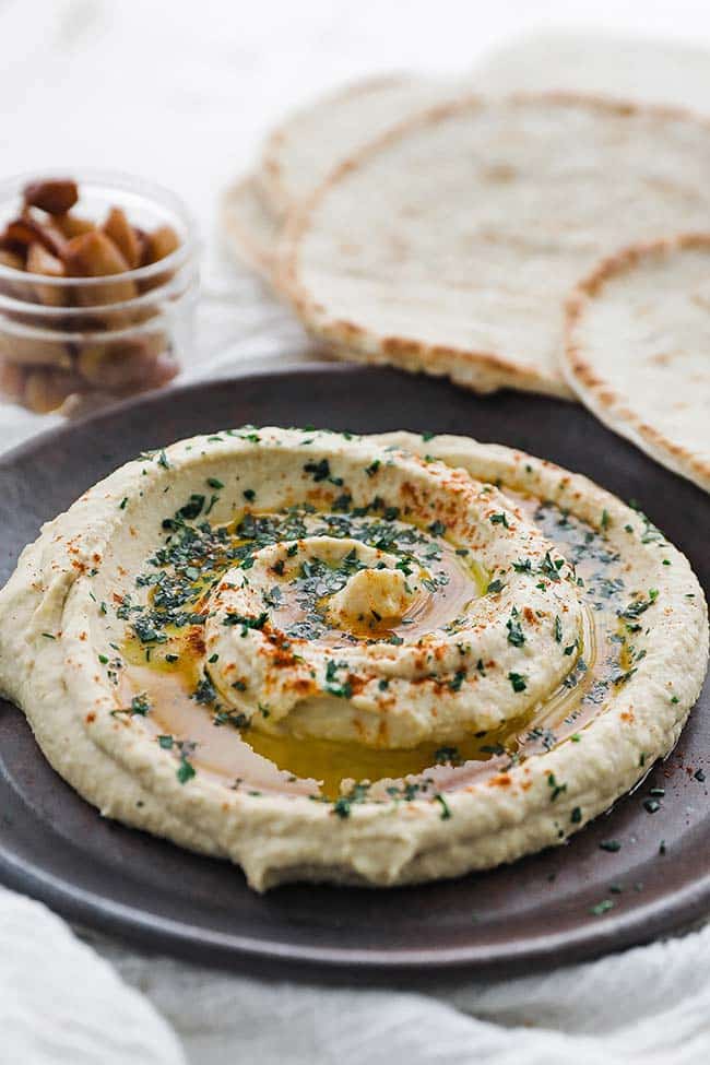 plate of homemade hummus with olive oil and pita bread