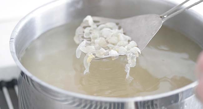 cooked garbanzo beans shells being removed from water