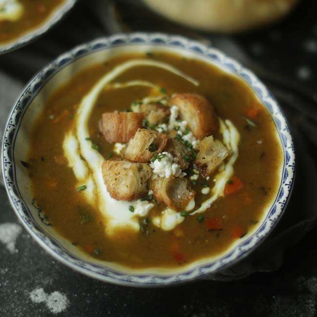 Mulligatawny Soup Recipe in a bowl with croutons and goat cheese garnishes