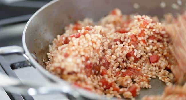 stirring rice in a pan with tomatoes