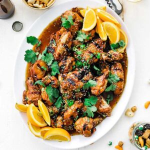 chicken wings in a sauce with oranges on a platter