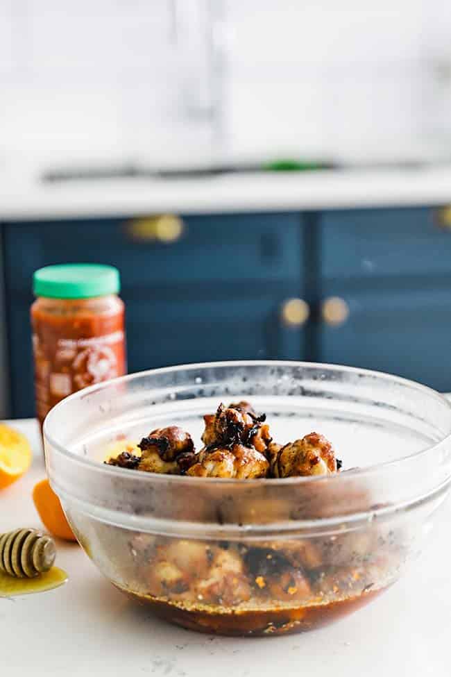 grilled chicken wings in a bowl with chili garlic sauce