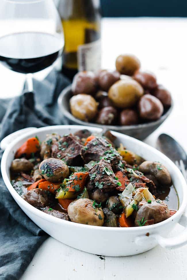 casserole dish of cooked beef with herbs, mushrooms and carrots