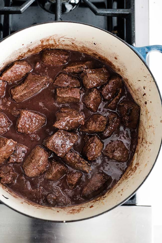 cubed beef with red wine cooking in a pot
