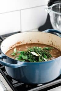 a large pot with beef stock and fresh herbs