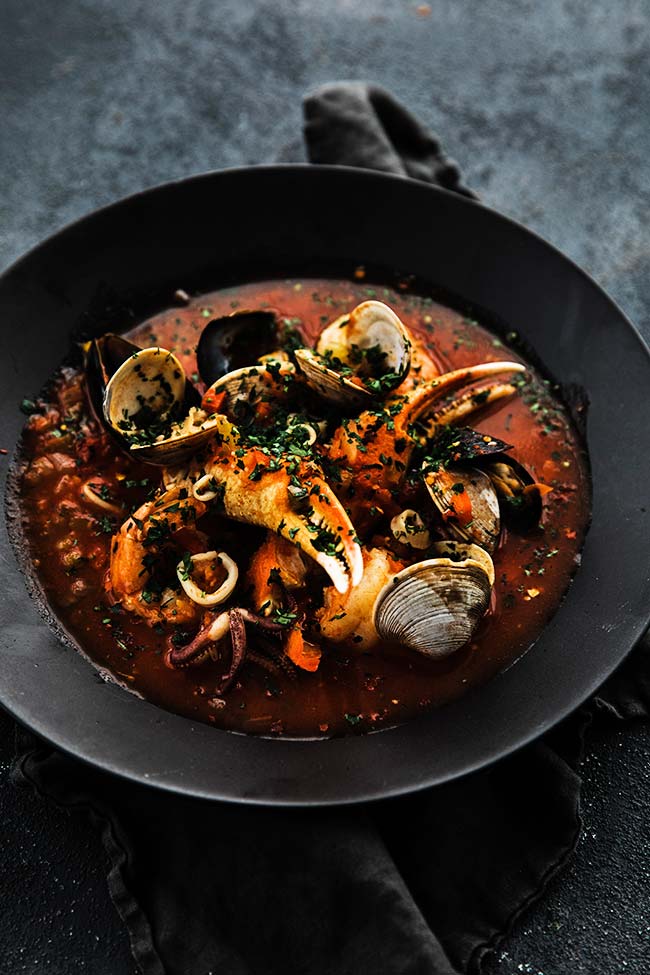 italian cioppino recipe in a large bowl with shrimp and clams
