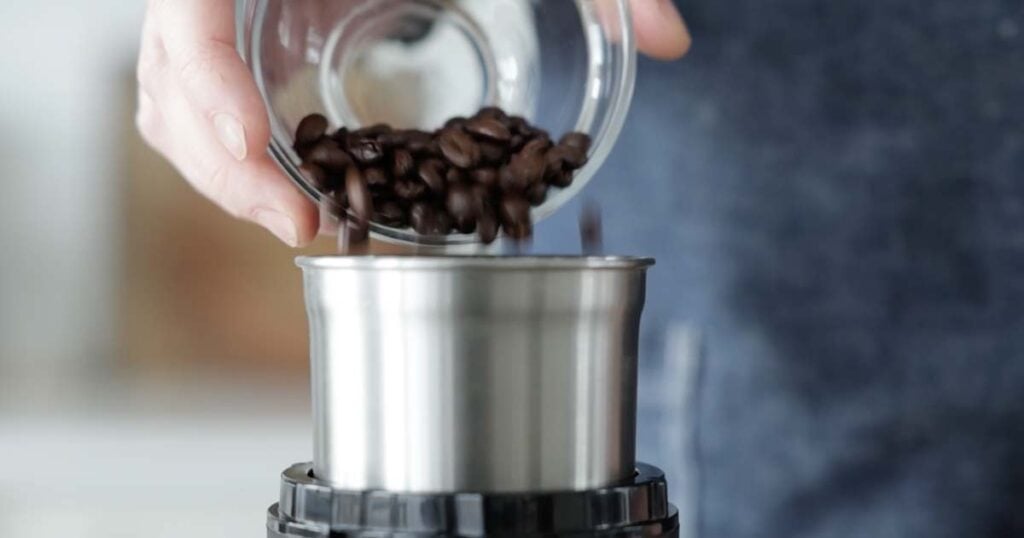 adding coffee beans to a grinder