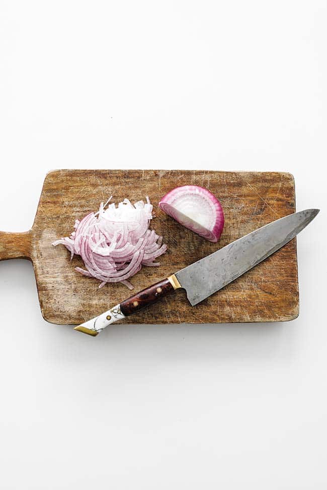 sliced red onions on a cutting board with a knife