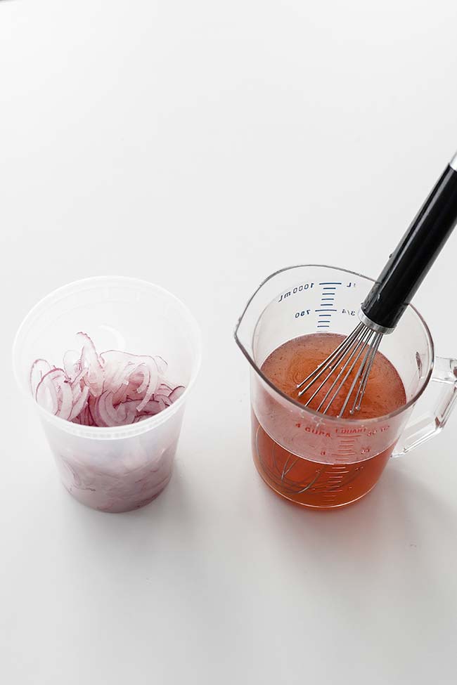 sliced red onions next to measuring cup of vinegar