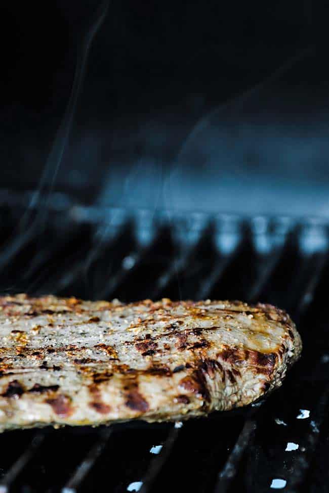 grilled flank steak on the grill with grill marks