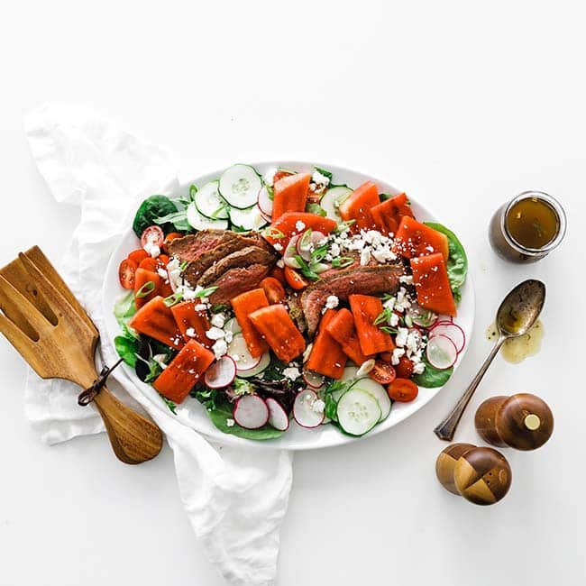 salad on a platter with water melon and steak