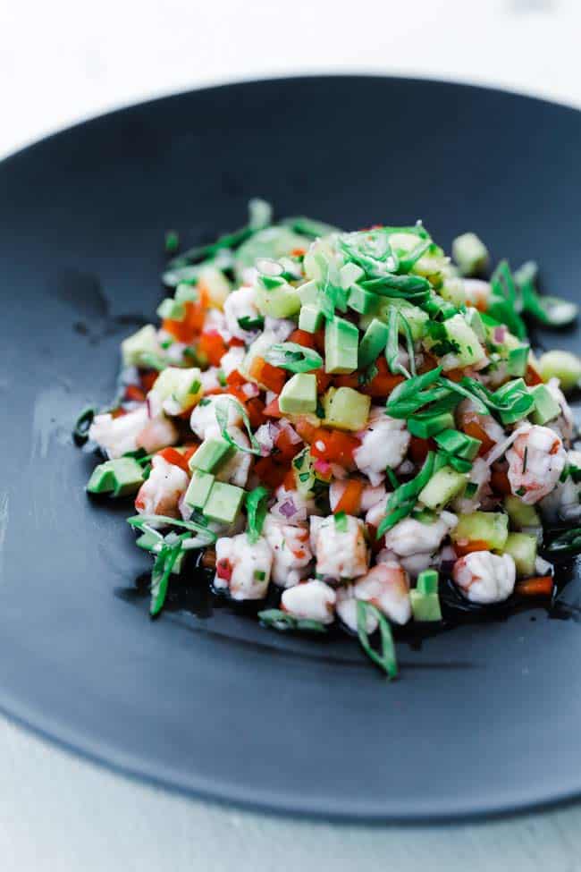 shrimp appetizer with red peppers, pineapple and green onions on black plate