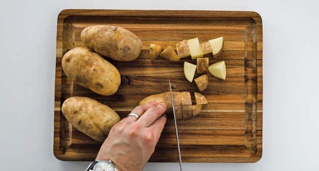 cubing russet potatoes on a cutting board