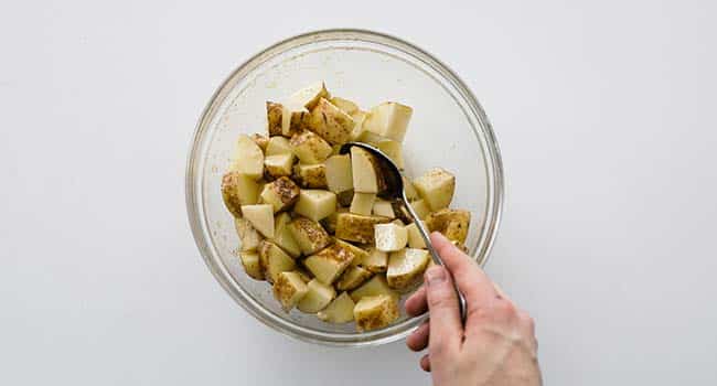mixing potatoes with olive oil in a bowl