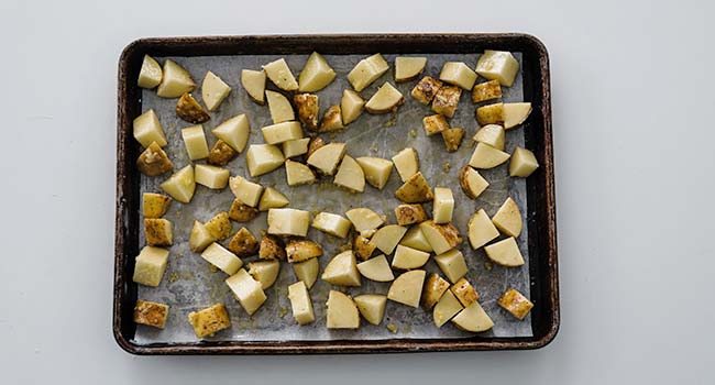 cubed potatoes spread out on a sheet tray 