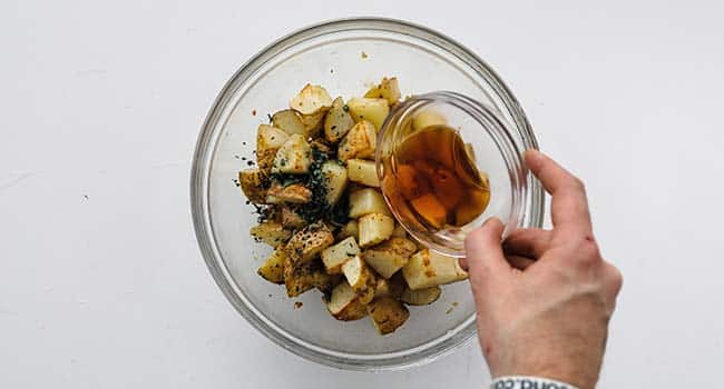 adding red wine vinegar to roasted herb potatoes