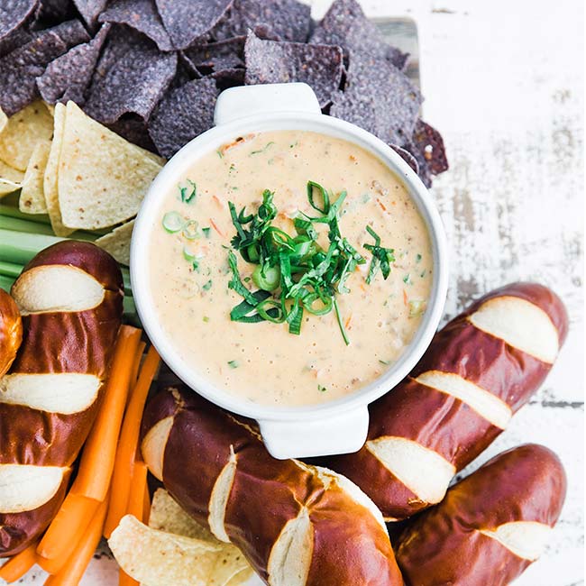 beer cheese dip recipe in a bowl served with chips and soft pretzels