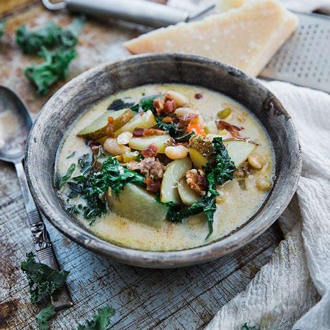 zuppa toscana soup with potatoes and kale in a bowl next to parmesan cheese