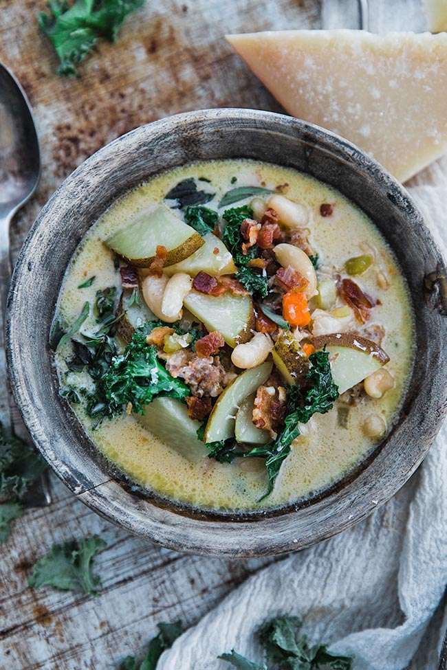 zuppa toscana with beans, kale, potatoes and parmesan cheese in a bowl