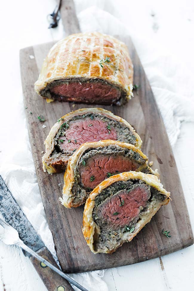 sliced beef wellington on a cutting board with a knife