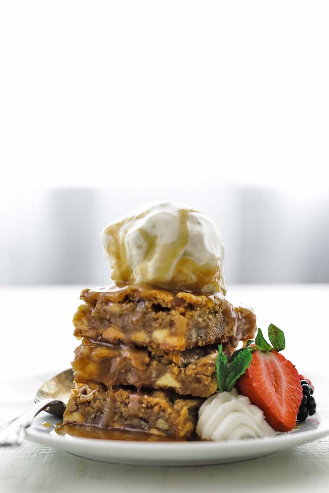 stack of blondies with ice cream, caramel, whipped cream and berries