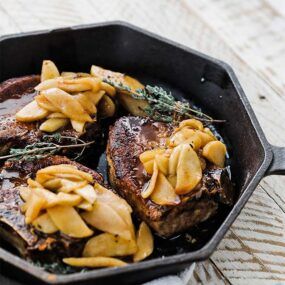 skillet of cooked pork chops with roasted apples