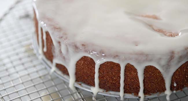 pouring glaze onto a lemon polenta cake