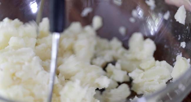 mashing potatoes in a bowl