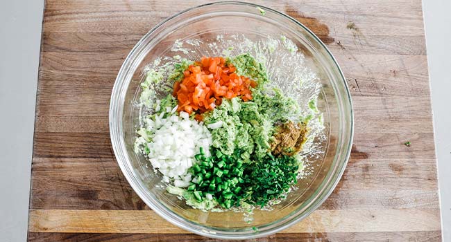 tomatoes, onions, and peppers in mashed avocado