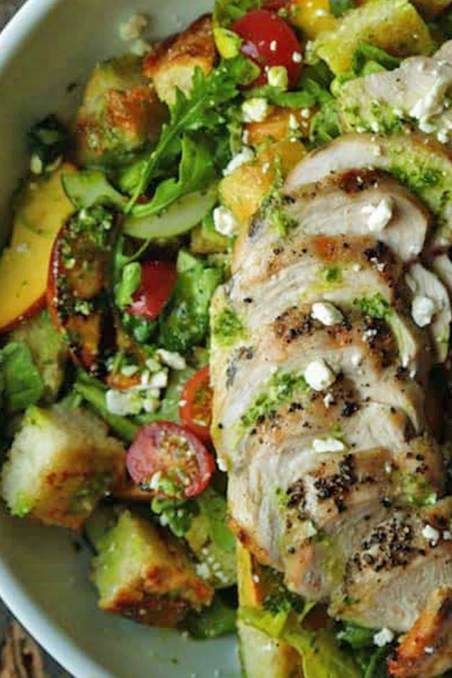 grilled chicken over a bed of greens with bread and tomatoes