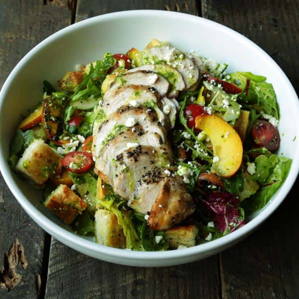 bowl of salad with bread, peaches, tomatoes and grilled chicken