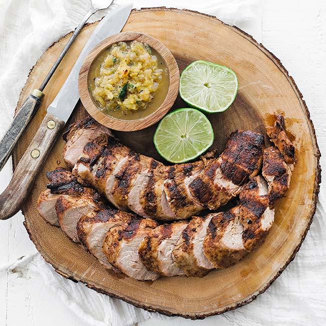 cutting board with sliced pork tenderloin and salsa