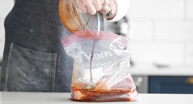 adding a spice rub to pork tenderloin in a plastic bag