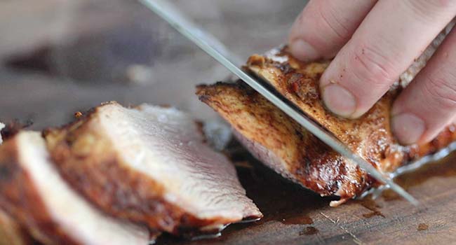 slicing grilled pork tenderloin on a cutting board