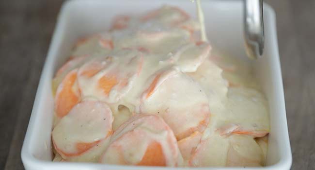 transferring creamy potatoes to a casserole dish