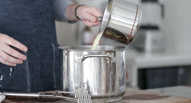 adding fat to a pot of cooked potatoes