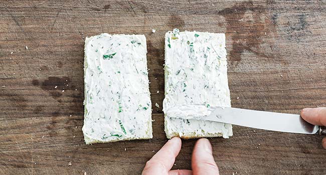 spreading cream cheese on bread