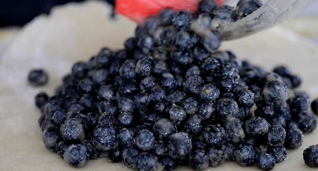 adding blueberries to the center of pie dough