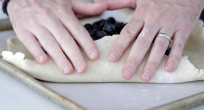 folding up the sides on a blueberry crostata