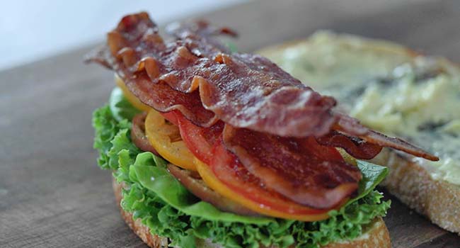 layering bacon onto a BLT sandwich