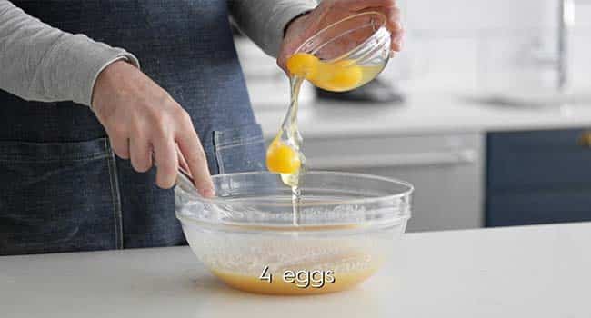 adding eggs to a bowl with melted butter