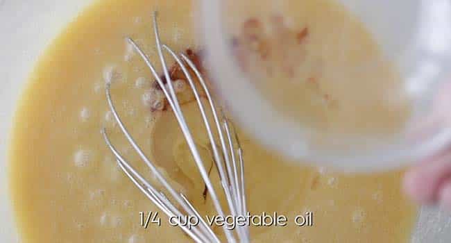 whisking vanilla extract into a bowl of melted butter and eggs