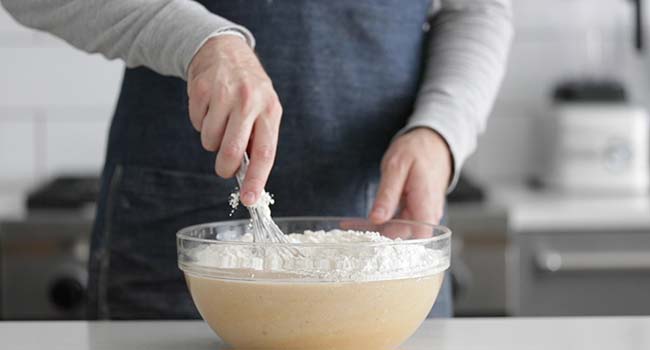 whisking flour in a bowl with melted butter and eggs