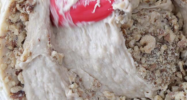 folding walnuts with flour into a bowl